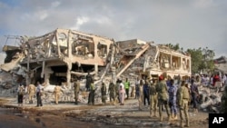 Somali security forces and others gather and search for bodies near destroyed buildings at the scene of Saturday's blast, in Mogadishu, Somalia, Oct. 15, 2017.