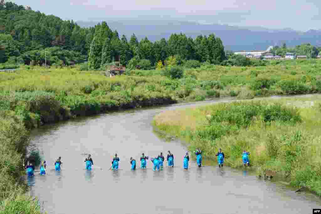 Police officers search for missing people in a river in Namie, near the striken TEPCO's Fukushima Dai-ichi nuclear plant in Fukushima prefecture, two and half years after the massive earthquake and tsunami, which killed more than 18,000 people in northern Japan.