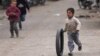 一个叙利亚小男孩在街上推着轮胎奔跑