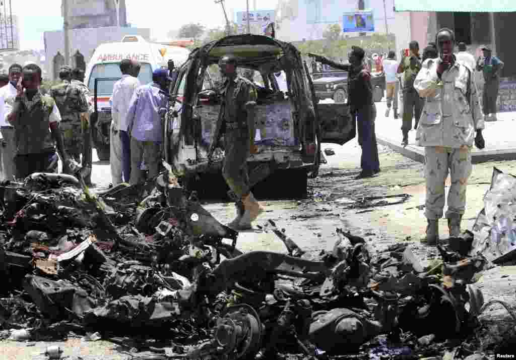 A soldier uses his mobile phone to record the wreckage of vehicles at the scene of an explosion in Mogadishu, Somalia, March 18, 2013.