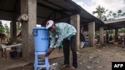 A man washes with chlorinated water, a disinfectant, at the Congo Air Market on the airport road east of Mbandaka.