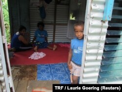 Rusiate, the 3-year-old son of Laisiasa Caukiuai, the headman of Tutua, a village on Fiji's Koro island, peers out the door of a tin-sided house owned by family members in Suva, Fiji's capital, Feb. 9, 2018.