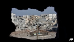 FILE - An area controlled by the Islamic State group, past the Qada Azadi roundabout, foreground, in Kobani, Syria, Nov. 20, 2014.