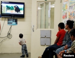 FILE - A detained immigrant child watches a cartoon while awaiting the arrival of U.S. first lady Melania Trump with other young detained immigrants at a U.S Customs and Border Patrol immigration detainee processing facility in Tucson, Arizona, June 28, 2018.