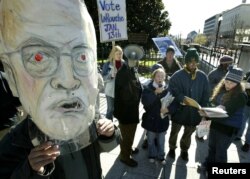 FILE - Supporters of Democratic presidential nominee Lyndon Larouche, including one wearing a mask lampooning Vice President Dick Cheney, protest outside the Old Executive building near the White House in Washington, Dec. 1, 2003.