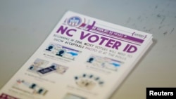 FILE - A pile of government pamphlets explaining North Carolina's voter identification law sits on table at a polling station.