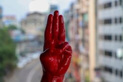 一名反軍事政變抗議者用紅漆染紅的手舉手行三指禮。 （2021年4月6日）