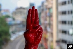 一名反军事政变抗议者用红漆染红的手举手行三指礼。（2021年4月6日）