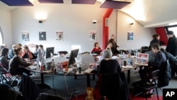 FILE - Editorial staff of the French satirical magazine Charlie Hebdo share the offices of the French newspaper Liberation, in Paris, Jan. 9, 2015.