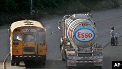 Un autobús público pasa por un camión de distribución de gasolina propiedad de Esso Standard Oil cuando sale de una refinería en Managua, el jueves 6 de diciembre de 2007. 