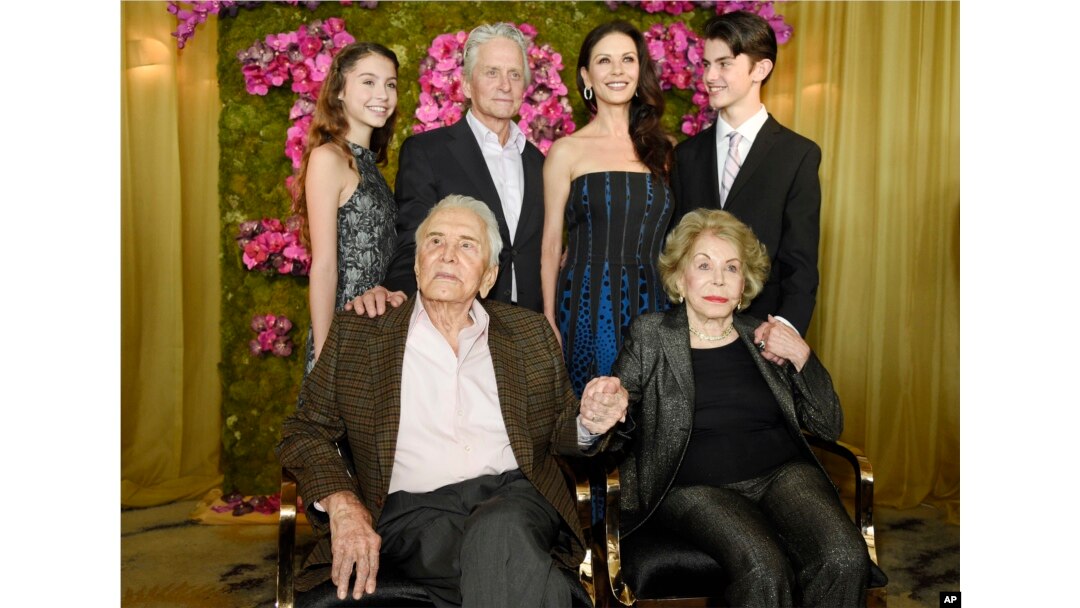 Actor Kirk Douglas (seated left) holds hands with his wife Anne Douglas as they pose with family members, their son Michael (standing second left), his wife Catherine Zeta-Jones (standing second right), and their children, Carys Zeta Jones (left) and son Dylan during Kirk's 100th birthday party at the Beverly Hills Hotel, Dec. 9. 2016, in Beverly Hills, Calif.