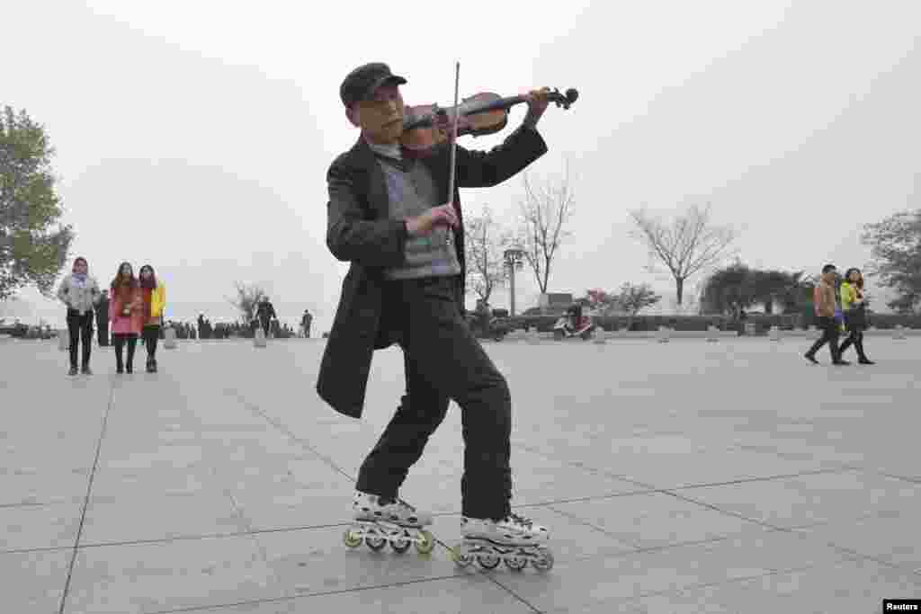 A man plays violin as he roller-skates on a sqauare on a hazy day in Nanjing, Jiangsu province, China.