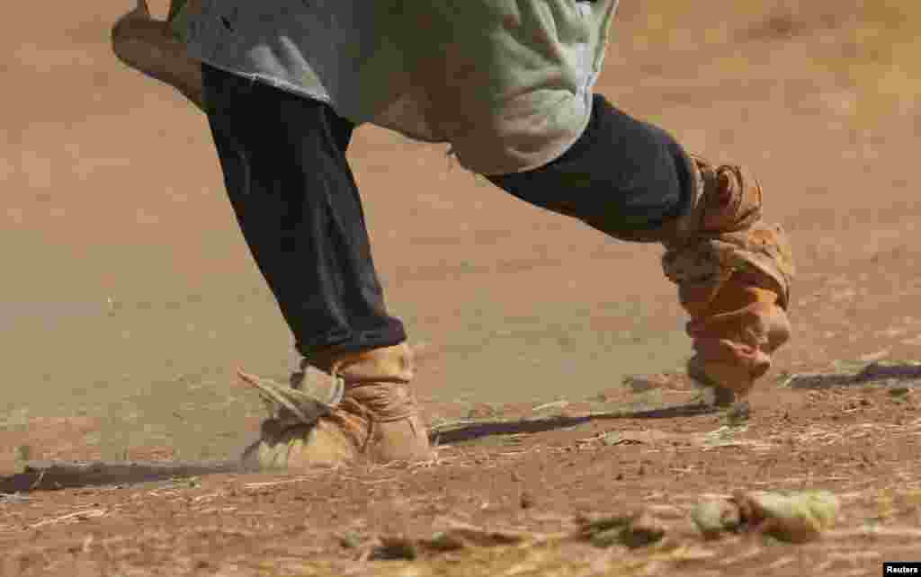 A displaced woman from the minority Yazidi sect, fleeing violence from forces loyal to the Islamic State in Sinjar town, covers her feet with clothes as she walks towards the Syrian border, on the outskirts of Sinjar mountain, near the Syrian border town 