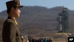A crowd of media gather around a North Korean official on a road in front of North Korea's Unha-3 rocket, slated for liftoff between April 12-16, stands at Sohae Satellite Station in Tongchang-ri, North Korea, April 8, 2012