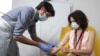 In this handout photo released by the University of Oxford a doctor takes blood samples for use in a coronavirus vaccine trial in Oxford, England, Thursday June 25, 2020. 