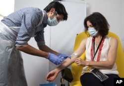 FILE - In this handout photo released by the University of Oxford a doctor takes blood samples for use in a coronavirus vaccine trial in Oxford, England, Thursday June 25, 2020.