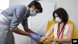 In this handout photo released by the University of Oxford a doctor takes blood samples for use in a coronavirus vaccine trial in Oxford, England, Thursday June 25, 2020. Scientists at Oxford University say their experimental coronavirus vaccine has been 