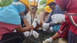 Hairunisa (baju putih) bersama sejumlah Ibu di desa Beka, Marawola, Kabupaten Sigi, Sulawesi Tengah mempraktekkan cara mengikat batang-batang besi yang digunakan untuk kebutuhan tiang bangunan rumah, 7 Desember 2019. (Foto: VOA/ Yoanes Litha)