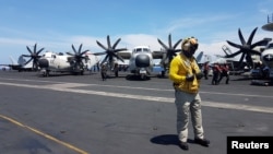 An air traffic controller guides aircraft landing on the deck of the USS Theodore Roosevelt, transiting the South China Sea April 10, 2018. 