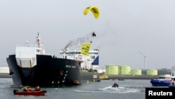 Một thành viên của Greenpeace trên chiếc dù lượn mang theo tấm biểu ngữ viết 'No Arctic Oil' (tạm dịch: Không khoan dầu ở Bắc Băng Dương) bay trên đầu chiếc tàu chờ dầu của Nga Mikhail Ulyanov ở cảng Rotterdam. '