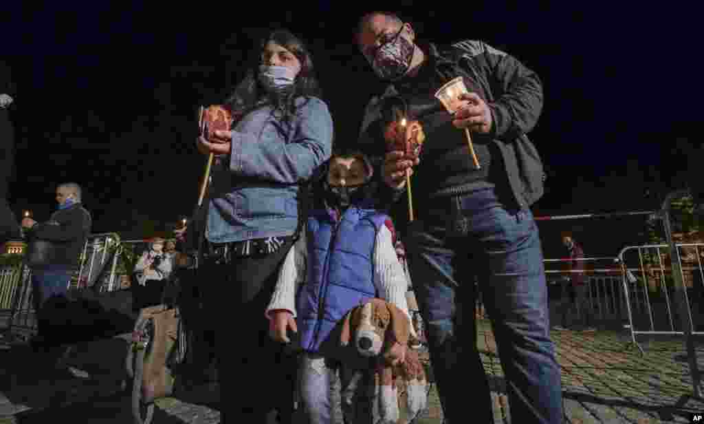 Una familia con máscaras protectoras posa para una foto mientras asisten a la misa de la Pascua Ortodoxa a medianoche frente a la catedral Alexander Nevsky en Sofía, Bulgaria, el domingo 19 de abril de 2020.