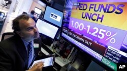 A trader watches a television screen on the floor of the New York Stock Exchange showing the rate decision of the U.S. Federal Reserve, in New York, Nov. 1, 2017.