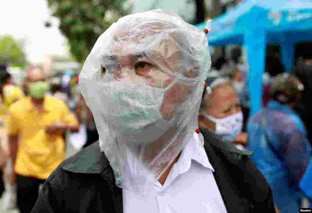A man wears a face covering to protect against the coronavirus disease as he lines up for filing forms to request three months of financial aid from the government in front of the Finance Ministry in Bangkok, Thailand.