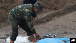 Seorang tentara Laos menutupi mayat korban kecelakaan terbang di sungai Mekong, kota Pakse, Laos. 