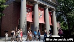 FILE - People are led on a tour on the campus of Harvard University in Cambridge, Massachusetts. Refugees worldwide will be able to take more than 1,000 online university courses for free.