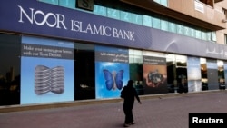 A woman walks past a branch of Noor Islamic Bank, which changed its name to Noor Bank in January 2014, in Dubai in 2010. 