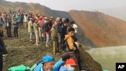 People stand while members of rescue team search for missing people at a jade mining area, Dec. 22, 2021, in Hpakant, Kachin State, northern Myanmar.
