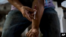 FILE - A man injects heroin, in an area popular with users behind an abandoned home in Humacao, Puerto Rico, Dec. 14, 2018. 