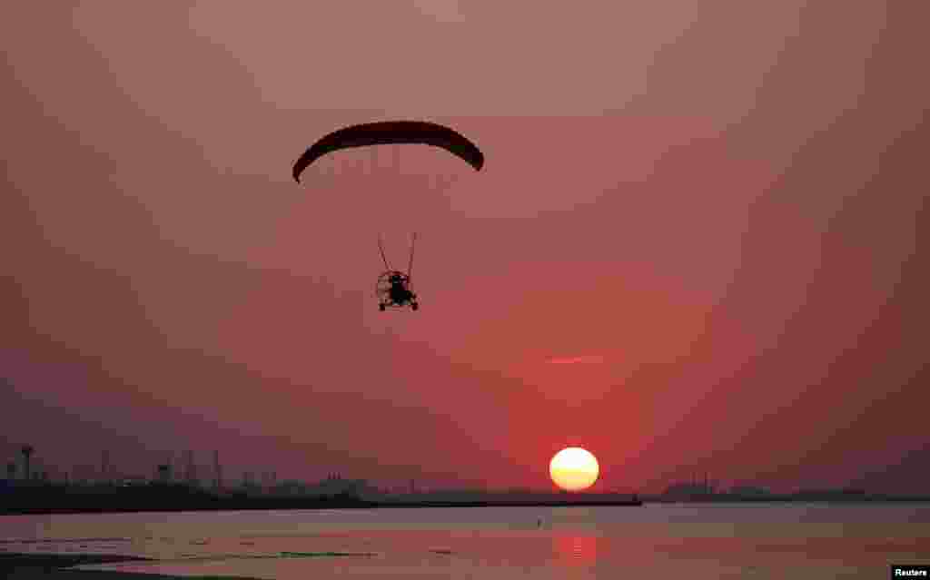 A man flies his powered paraglider over Marquette Beach as the sun sets in Gary, Indiana, USA, Sept. 6, 2013.