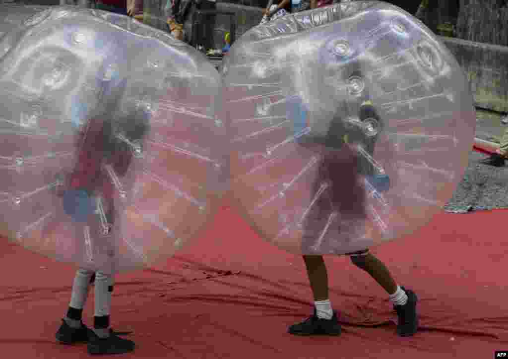Two kids inside plastic balloons play at the Los Caobos park, as part of the carnival celebration called "Carnavales Felices y Bioseguros 2021" in Caracas, Venezuela, Feb. 15, 2021.