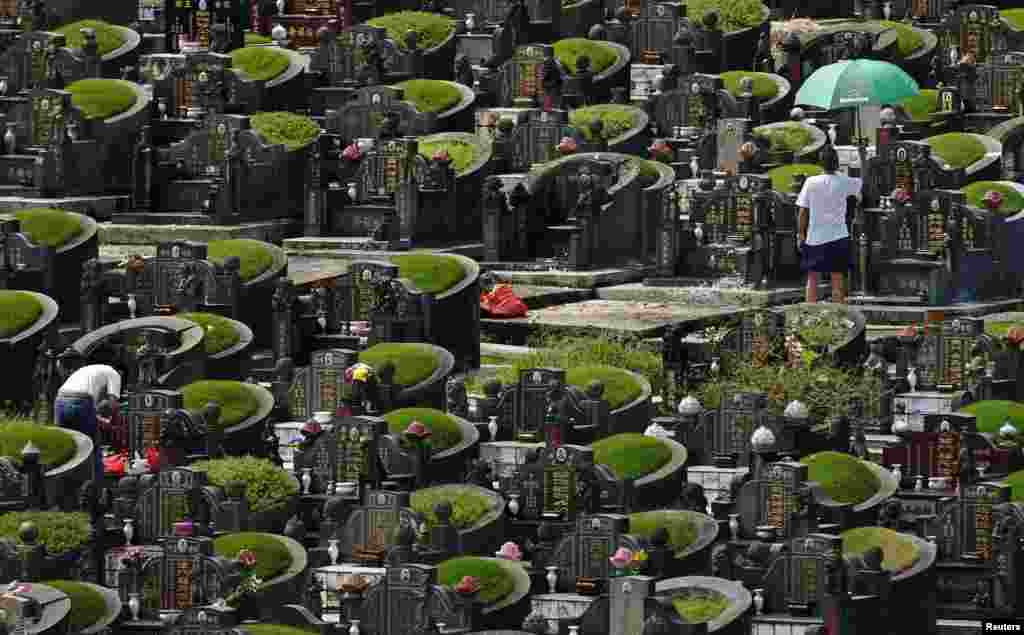 Men visit the graves of their ancestors during the Qing Ming Festival, or Tomb Sweeping Day, at a Chinese cemetery in Singapore. The festival, which falls on April 4 this year, is a day for the Chinese to remember and honor their ancestors.
