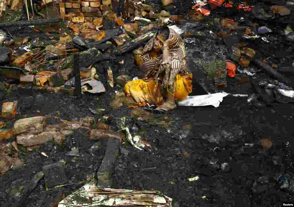 Taramuni Ray, 62, cries as she sits on the remains from her burned hut after a fire broke out at a slum in Kolkata, India.