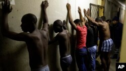 Men stand against a wall as police officers search their room during a raid at an Alexandra township hostel considered a hot spot for anti-immigrant attacks in Johannesburg, South Africa, April 23, 2015.