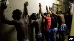 Men stand against a wall as police officers search their room during a raid at an Alexandra township hostel considered a hot spot for anti-immigrant attacks in Johannesburg, South Africa, April 23, 2015.
