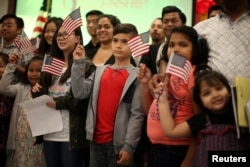 Children say the pledge of allegiance during a ceremony to present citizenship certificates to young people who earned citizenship through their parents, in Los Angeles, California, May 31, 2017.