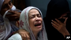 A Pakistani mother, center, mourns over the death of her son who was killed in a bomb explosion, in Karachi, Pakistan, Aug. 7, 2013