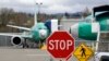 Des Boeing 737 MAX 8 sont garés derrière un panneau d'arrêt indiquant un passage à niveau dans une usine de production de Boeing Co., le lundi 8 avril 2019, à Renton, Etat de Washington, Etats-Unis. (AP Photo/Elaine Thompson)