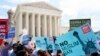 Protesters hold up signs and call out against the Supreme Court ruling upholding President Donald Trump's travel ban outside the the Supreme Court in Washington, June 26, 2018.