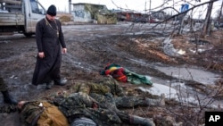 FILE - An Orthodox priest views bodies of killed Ukrainian soldiers at a checkpoint captured by pro-Russian rebels at the eastern Ukraine town of Krasniy Partizan, Jan. 24, 2015. Fighting has eased but continues despite several cease-fires.