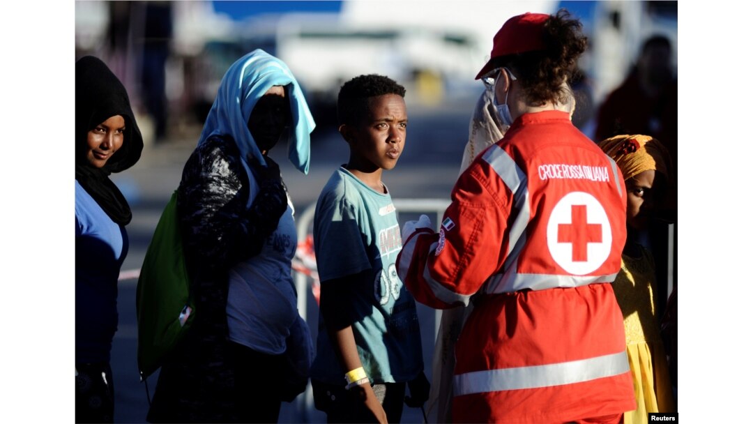 Migrants stand in a line in front of Red Cross member after disembarking from the Italian navy ship Borsini in the Sicilian harbor of Palermo, southern Italy, July 20, 2016.