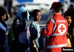 Migrants stand in a line in front of Red Cross member after disembarking from the Italian navy ship Borsini in the Sicilian harbor of Palermo, southern Italy, July 20, 2016.