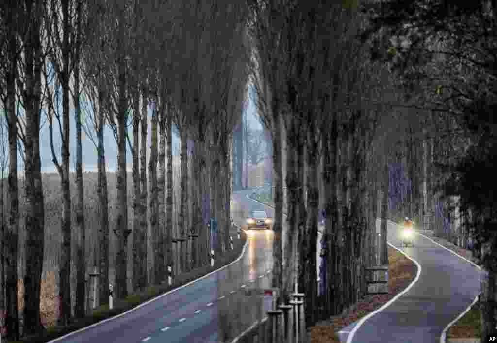 A man rides his bike next to a car in an alley leading to the Reichenau island near Konstanz, southern Germany.