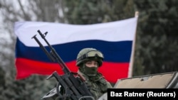 A Russian flag behind an armed servicemen on top of a Russian army vehicle outside a Ukrainian border guard post in the Crimean town of Balaclava. (File)