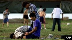 FILE - A small group of Muslim refugees pray at sunset while others play soccer at an Australian-run camp for asylum seekers on the small Pacfic island of Nauru, Sept. 20, 2001. Australia run similar camps on Manus Island in Papua New Guinea.