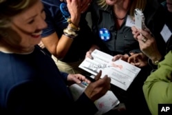 Democratic presidential candidate Hillary Clinton signs a vote-by-mail ballot letter as she greets volunteers at a campaign field office in San Francisco, Oct. 13, 2016.