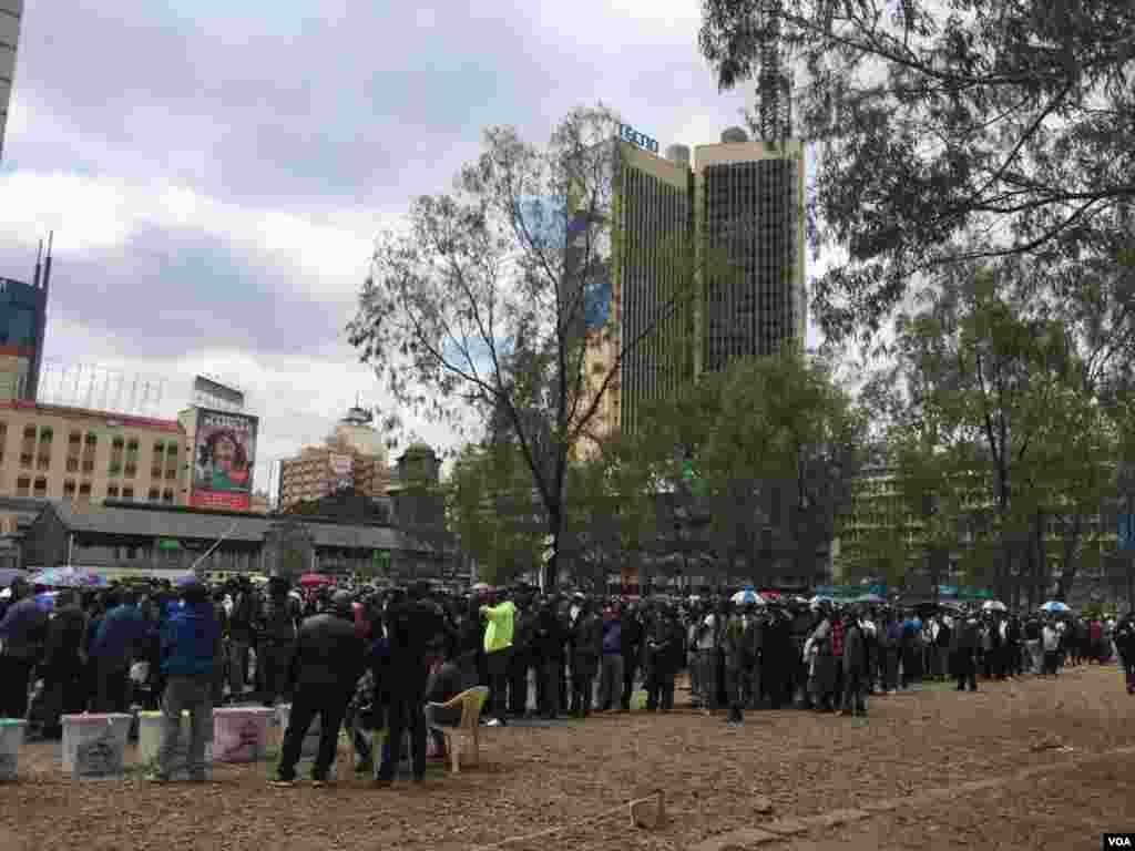 People queue to vote at a parking lot that has been temporarily converted into polling center, in downtown Nairobi, Kenya, Aug. 8, 2017. (J. Craig/VOA)